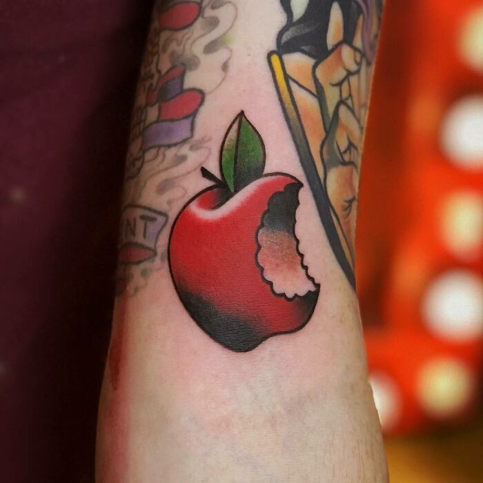 Tattoo of a bitten red apple on an arm, part of a collection of delicious food tattoos.