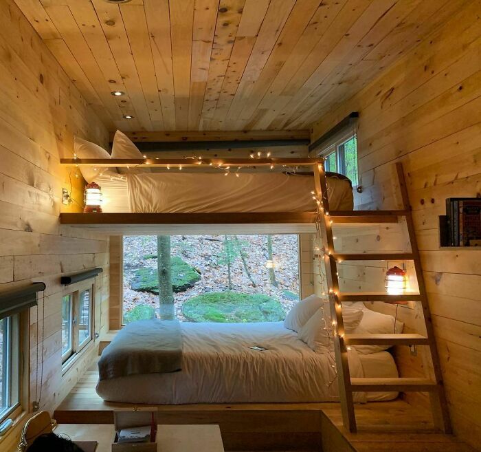 Cozy tiny house interior with wooden bunk beds and warm lighting, creating a charming and inviting atmosphere.