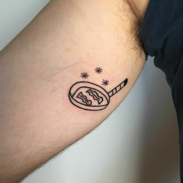 Minimalist bacon food tattoo on arm with stars above.