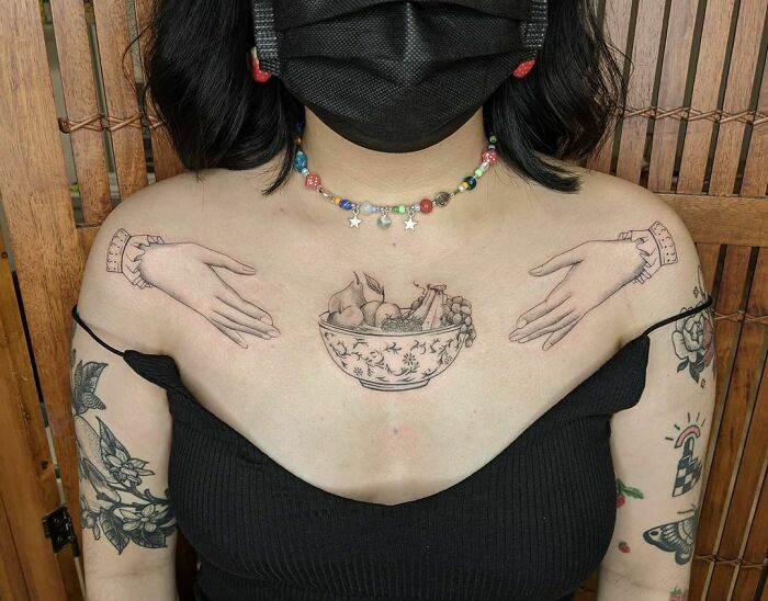 Chest tattoos featuring hands and a fruit bowl design, showcasing delicious food ink art.