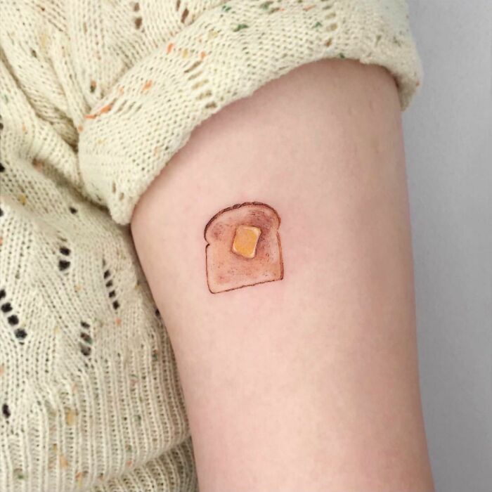 Food tattoo of toast with butter on an arm, showcasing a delicious design.