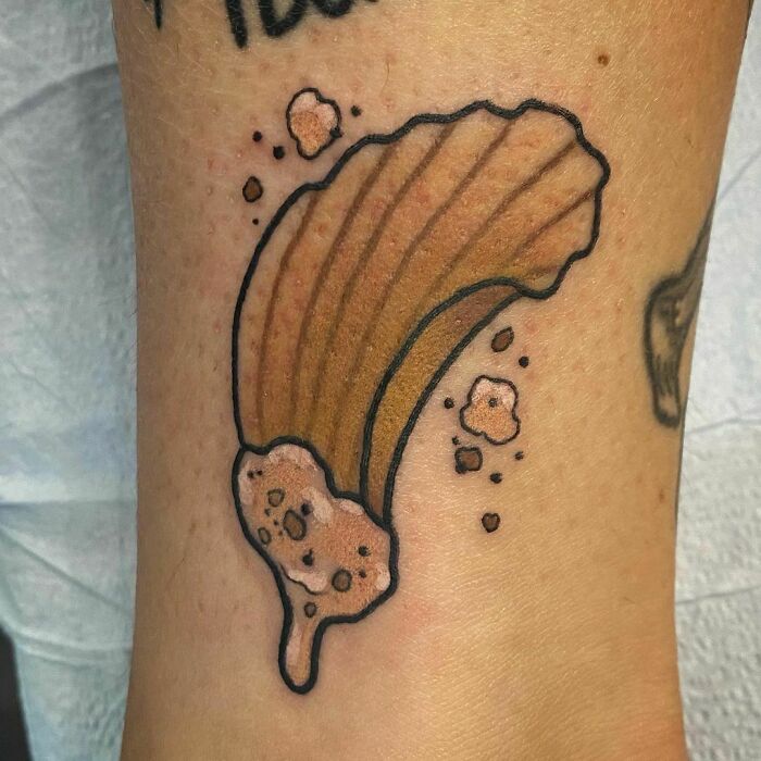 Food tattoo of a cartoon-style churro with sauce on skin.