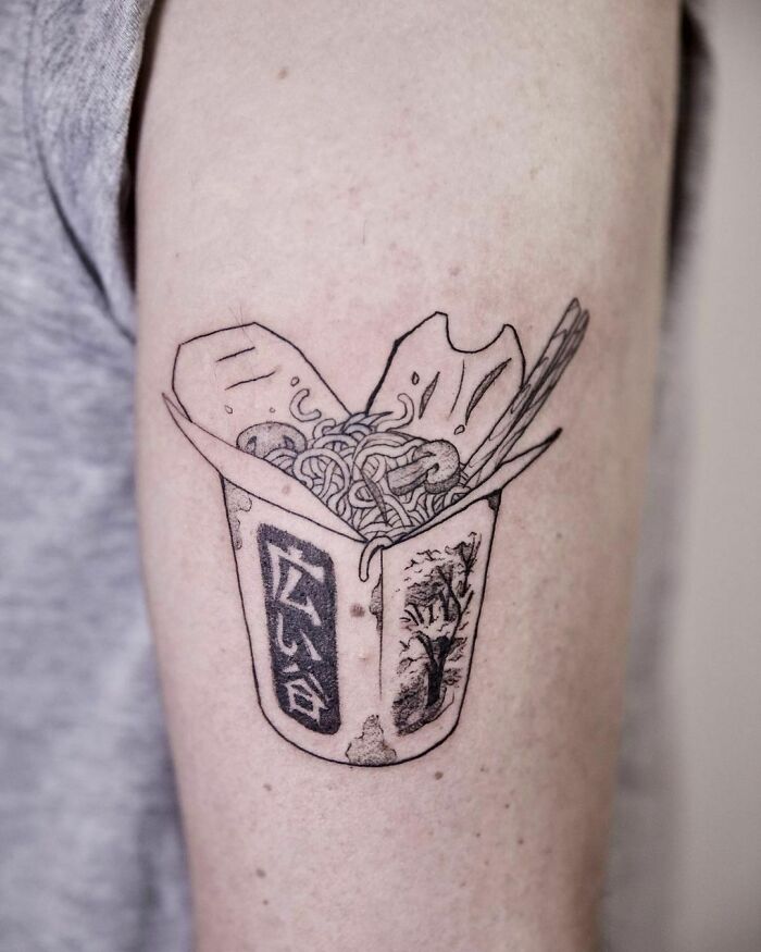 Tattoo of a noodle takeout box on an arm, showcasing delicious food ink art.