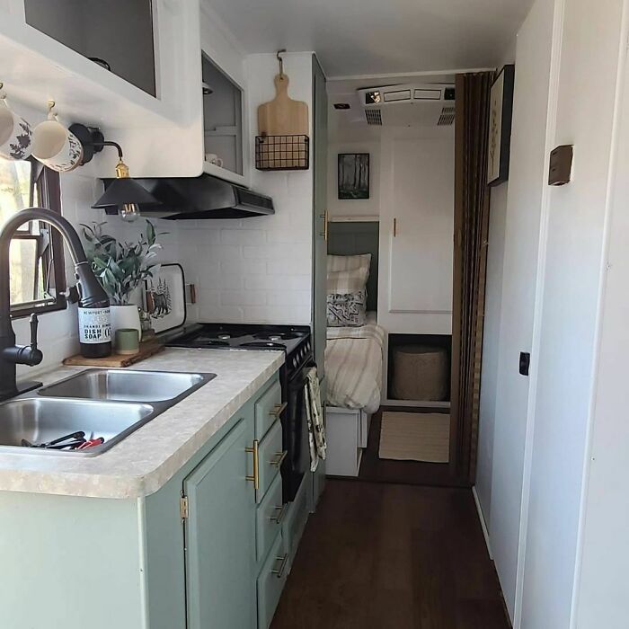 Compact white kitchen with green cabinets in a tiny house design featuring modern fixtures and efficient use of space.