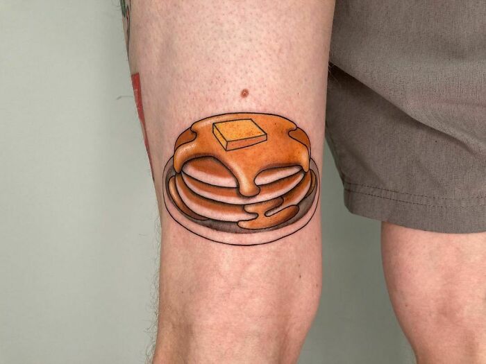 Pancake tattoo with syrup and butter on leg, showcasing delicious food ink.