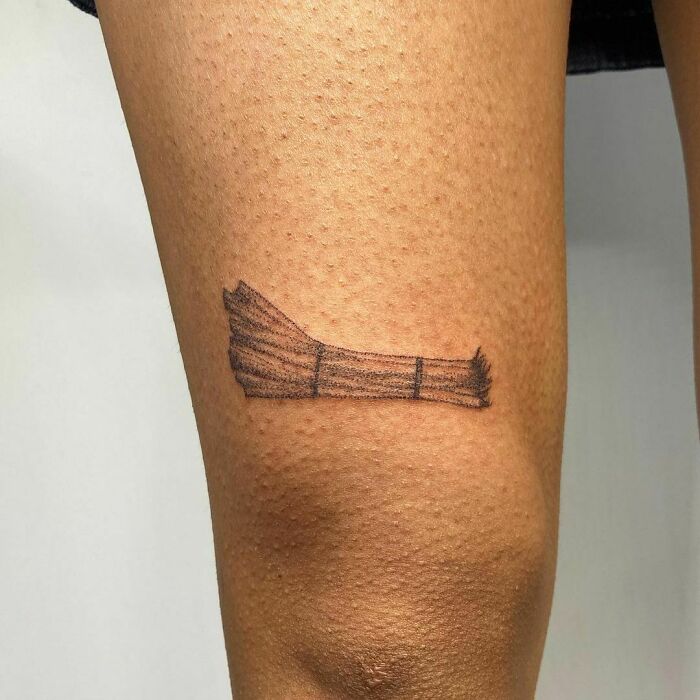 Minimalist asparagus food tattoo on a person's leg.