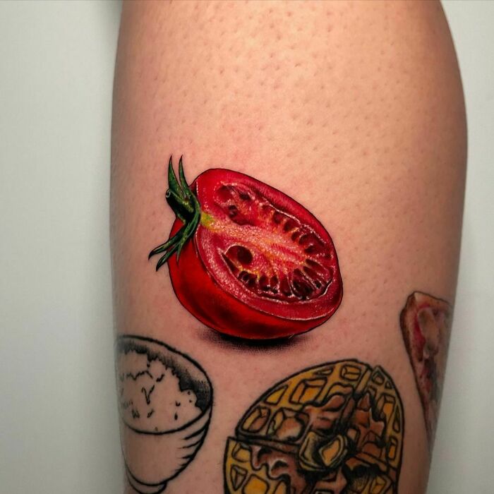 Red tomato tattoo with food ink designs features rice, waffle, and pizza slice.