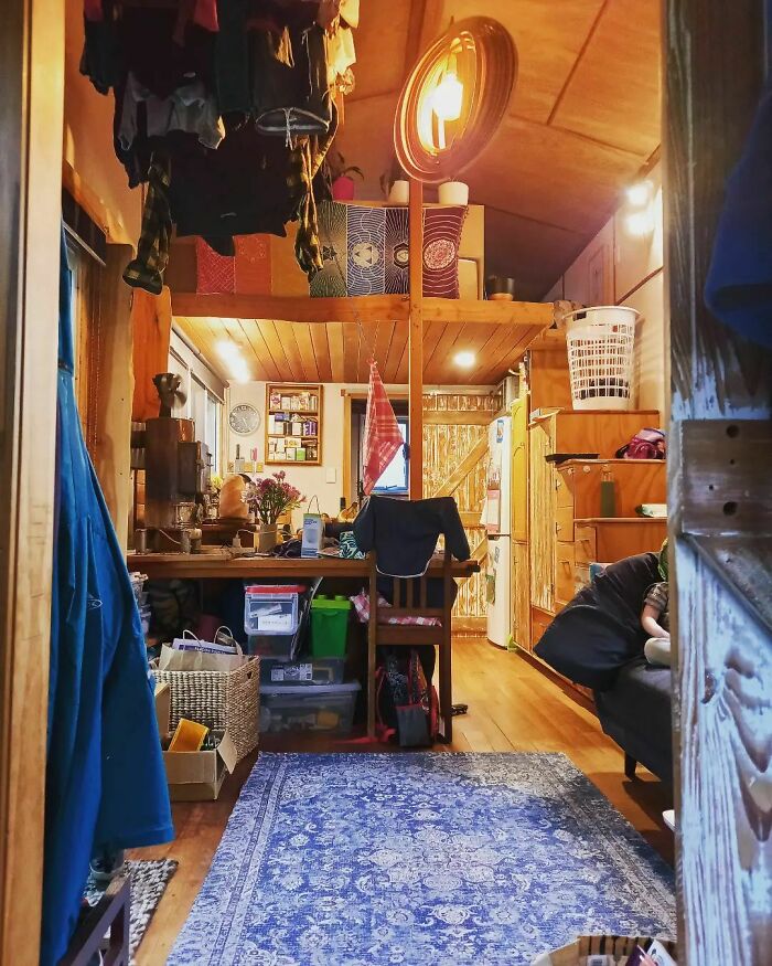 Cozy interior of a tiny house with wooden decor, loft bed, and decorative elements.