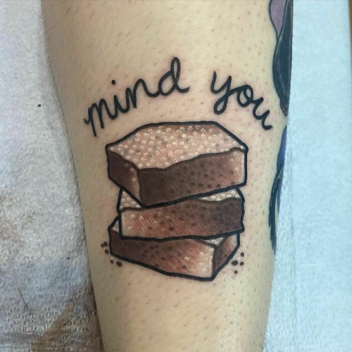 Food tattoo of stacked brownies with cursive text "mind you" above, inked on the arm.