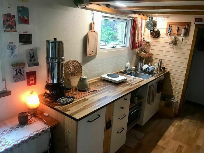 Cozy tiny house kitchen with wooden countertops and cabinets, featuring practical and space-saving design elements.