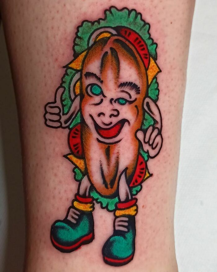 Cartoon-style hot dog tattoo with lettuce and tomato details, creatively representing delicious food tattoos.