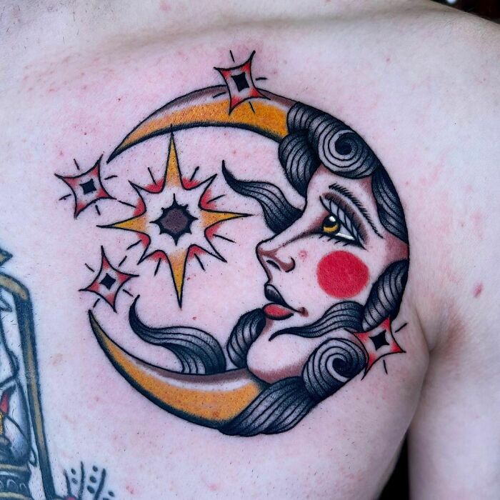 American traditional tattoo of a crescent moon with a woman's face, surrounded by stars, on shoulder.