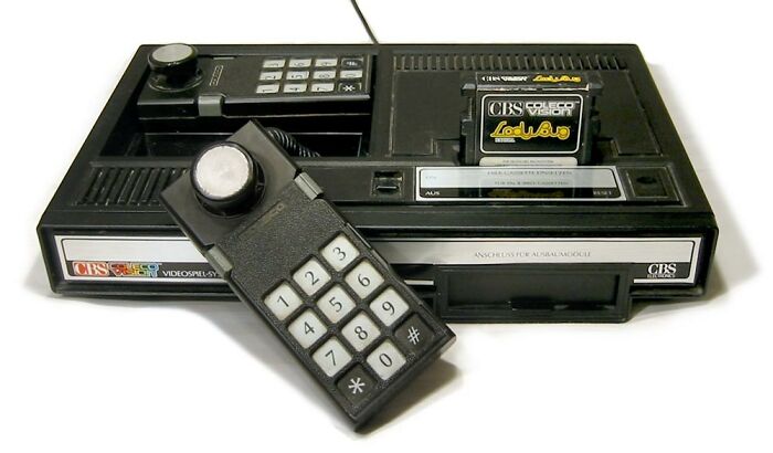 Vintage black gaming console with cartridge and remote control, one of the old gadgets that were trendsetters of their time