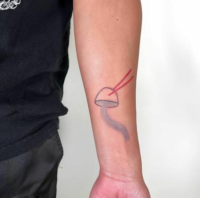 Food tattoo of a mushroom with chopsticks on a person's forearm.