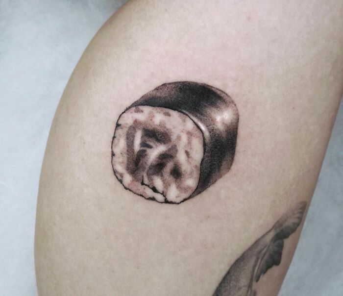 Sushi roll food tattoo on skin, showcasing detailed ink art.