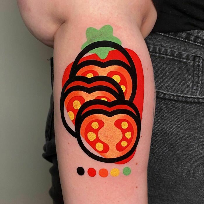 Watercolor tattoo of sliced tomato on an arm, showcasing vibrant food-inspired ink design.