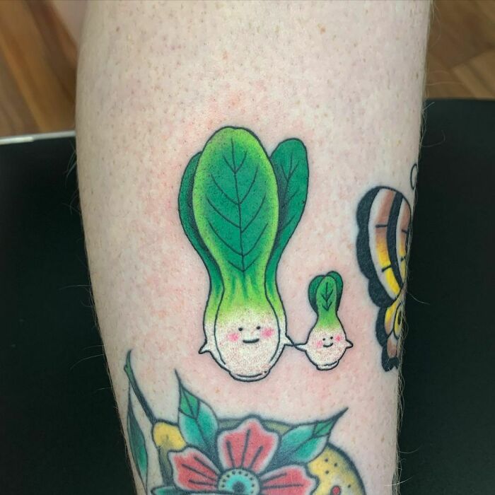 Food tattoo of smiling bok choy on arm with vibrant colors and playful design.