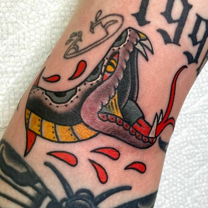 Close-up of an American traditional tattoo featuring a stylized snake with bold colors and intricate details.