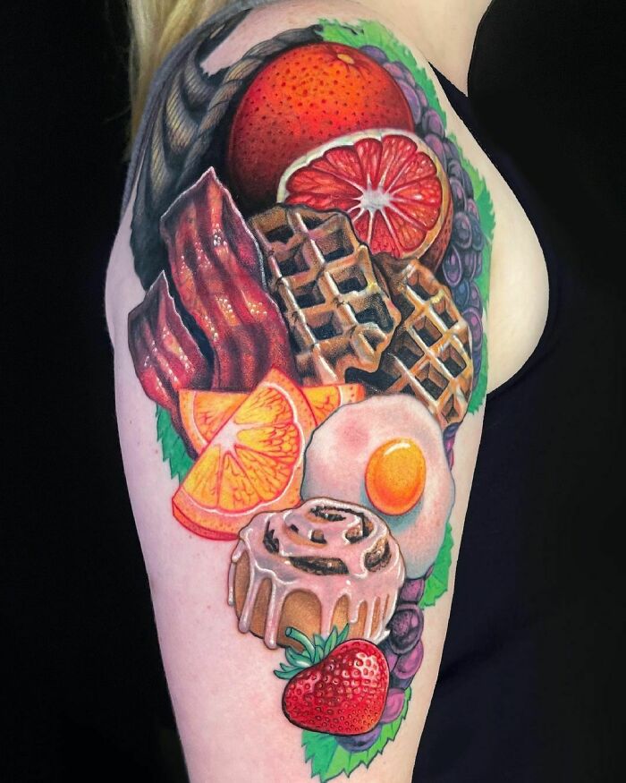 Colorful food tattoo showcasing waffles, bacon, eggs, and fruit.