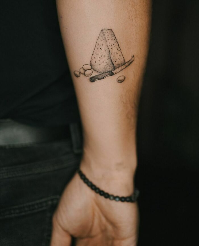 Tattoo of blue cheese and olives on forearm, showcasing food ink-spiration.