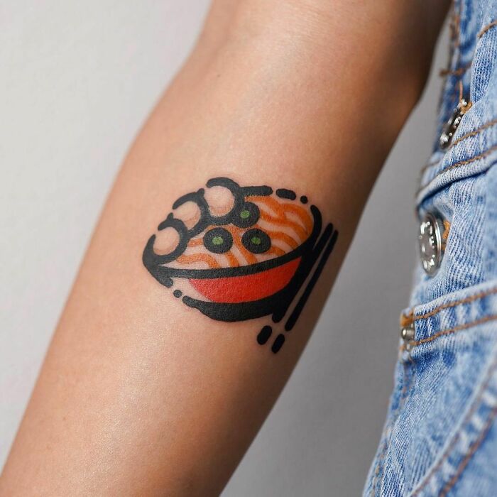 Minimalistic watercolor tattoo of noodles, featuring bold outlines and vibrant colors on arm.