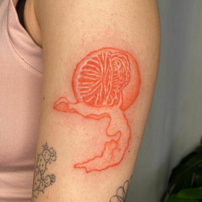 Orange food tattoo on arm, displaying intricate design.