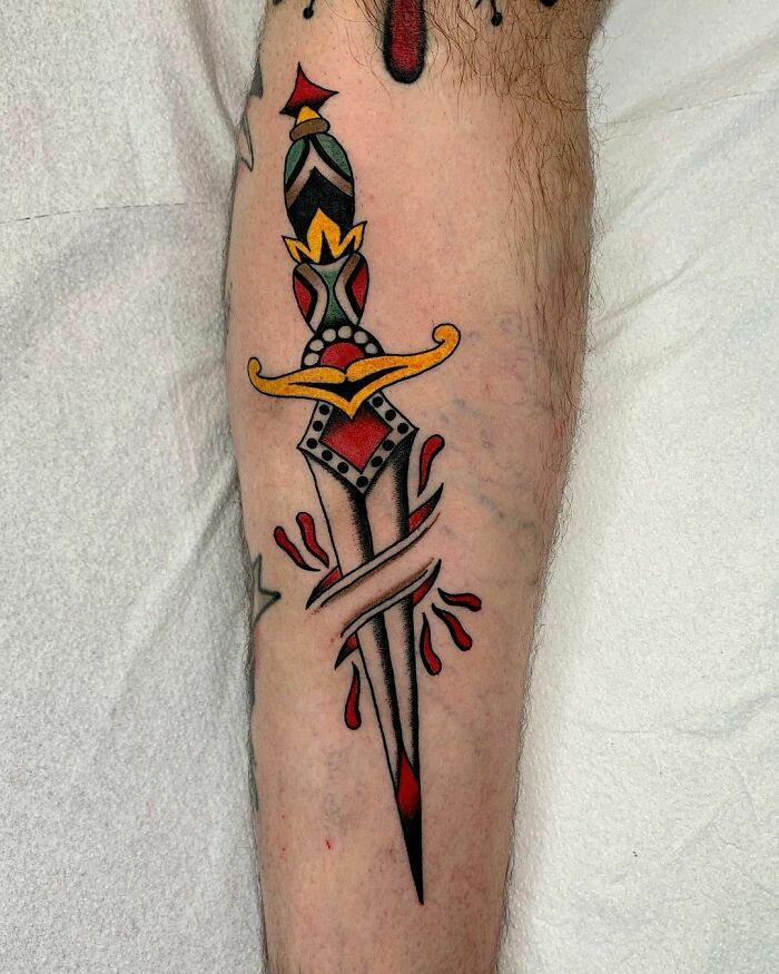 American traditional tattoo of a colorful dagger on forearm, featuring bold lines and vibrant colors.