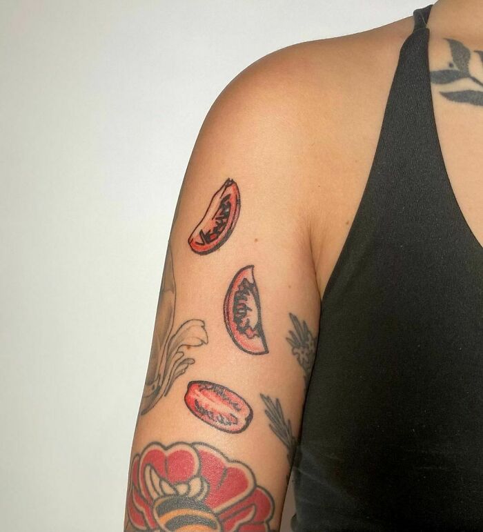 Tattoo of sliced tomatoes on an arm, showcasing a delicious food design.