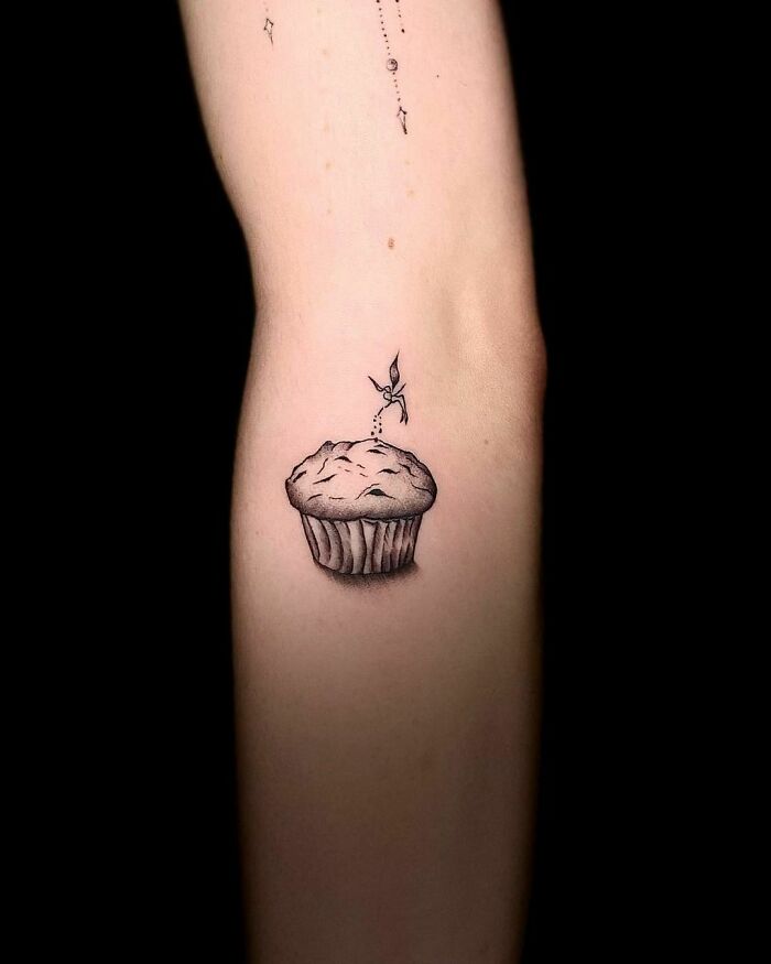 Cupcake tattoo on an arm, showcasing detailed food ink art.
