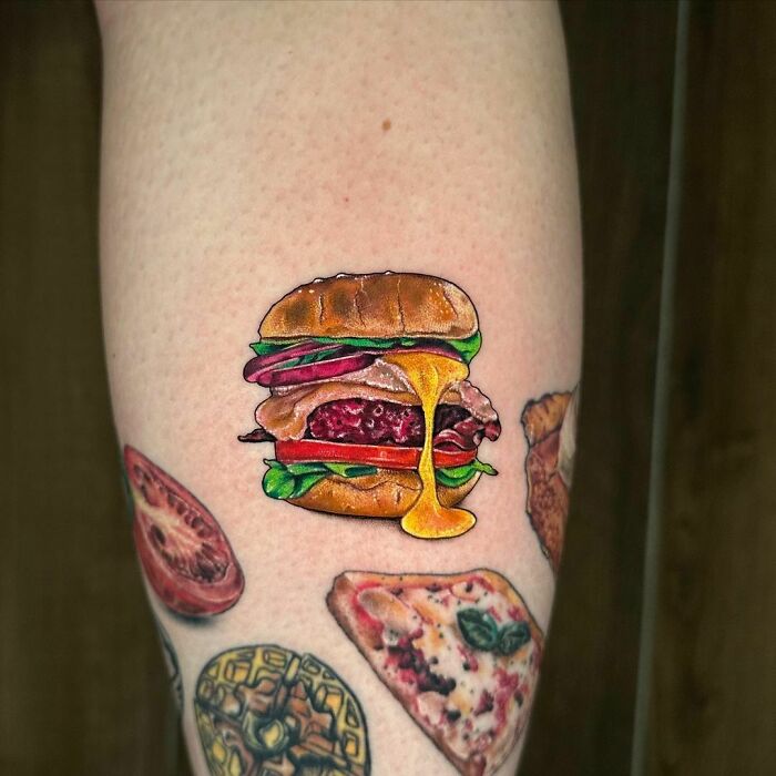 Realistic food tattoos featuring a juicy burger, slice of pizza, and fruit on skin, showcasing delicious ink art.