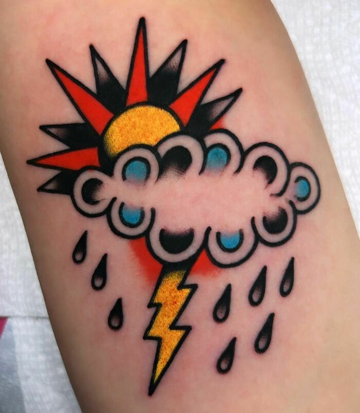 American traditional tattoo of a sun, cloud, lightning bolt, and raindrops on skin.