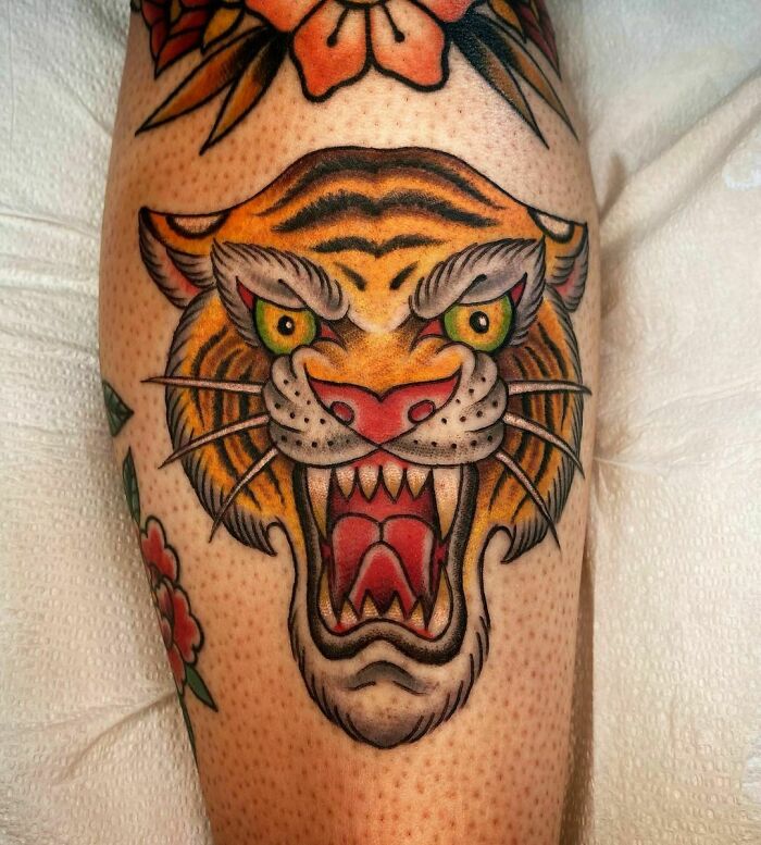 American traditional tattoo featuring a fierce tiger head with vibrant colors on an arm.