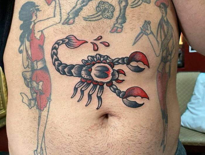 American traditional scorpion tattoo on a person's torso, featuring bold outlines and red accents.