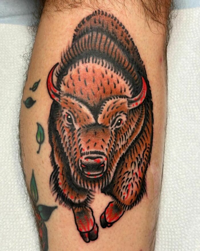 American traditional tattoo of a bison with bold lines and vibrant colors on a person's leg.