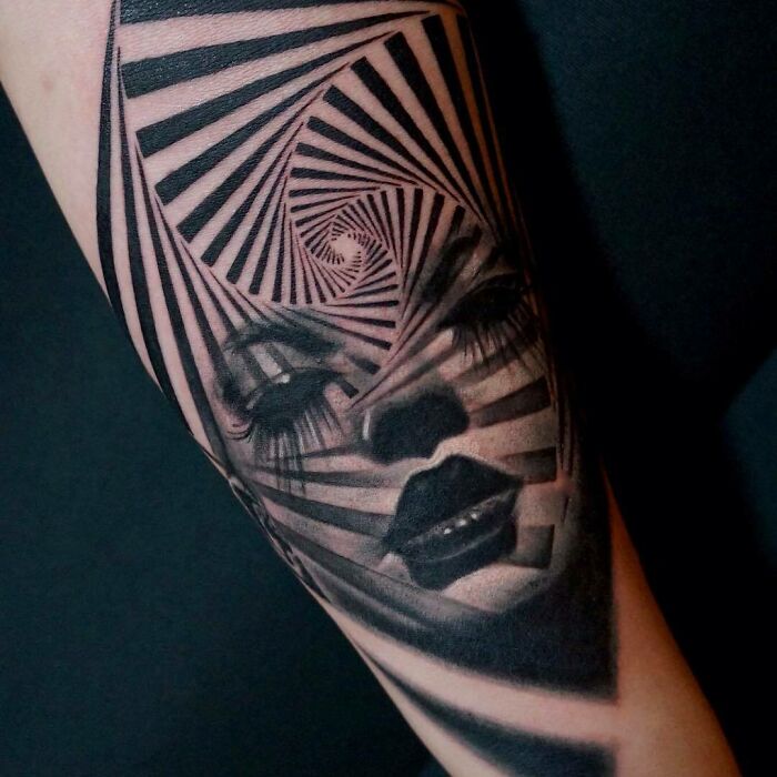 Optical illusion tattoo with spiral patterns creating a distorted face, playing tricks on your eyesight.