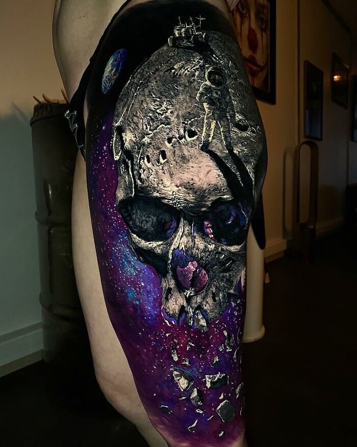 Tattoo art depicting a space scene with an astronaut on a skull against a cosmic background.