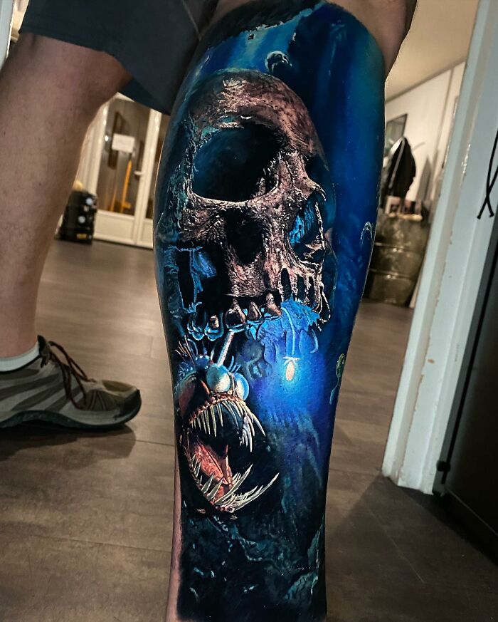 Skull and angler fish tattoo art on a leg, showcasing detailed and vibrant design.