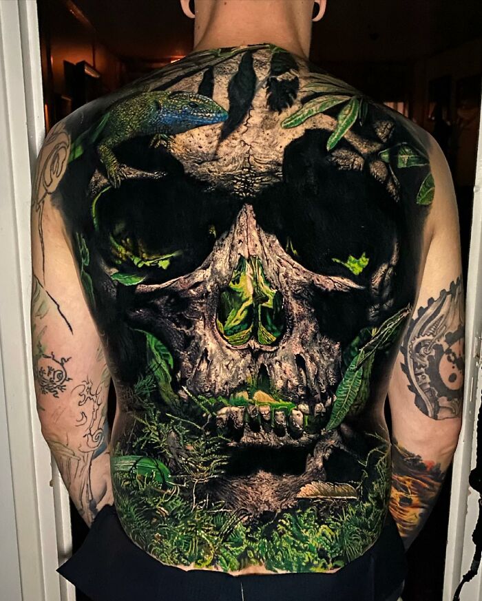 Tattoo art featuring a detailed skull and nature theme covering a person's back.