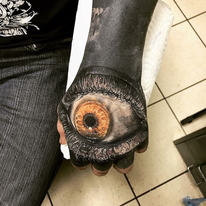 Realistic eye tattoo art on a person's hand, demonstrating advanced tattoo artistry skills.
