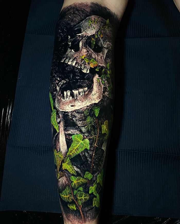 Leg tattoo with a realistic skull and vibrant green vines, showcasing advanced tattoo art techniques.