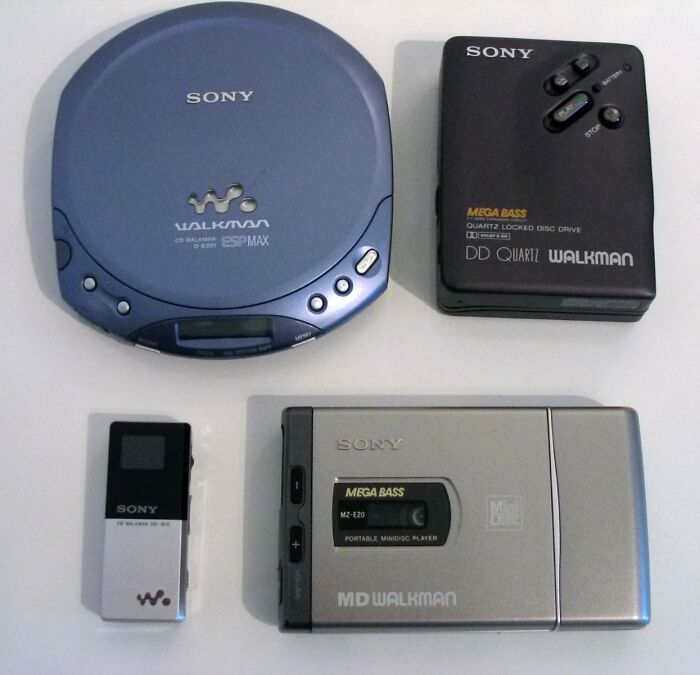 Four vintage Sony Walkman old gadgets including a portable CD player, MiniDisc player, and music players on a white surface.