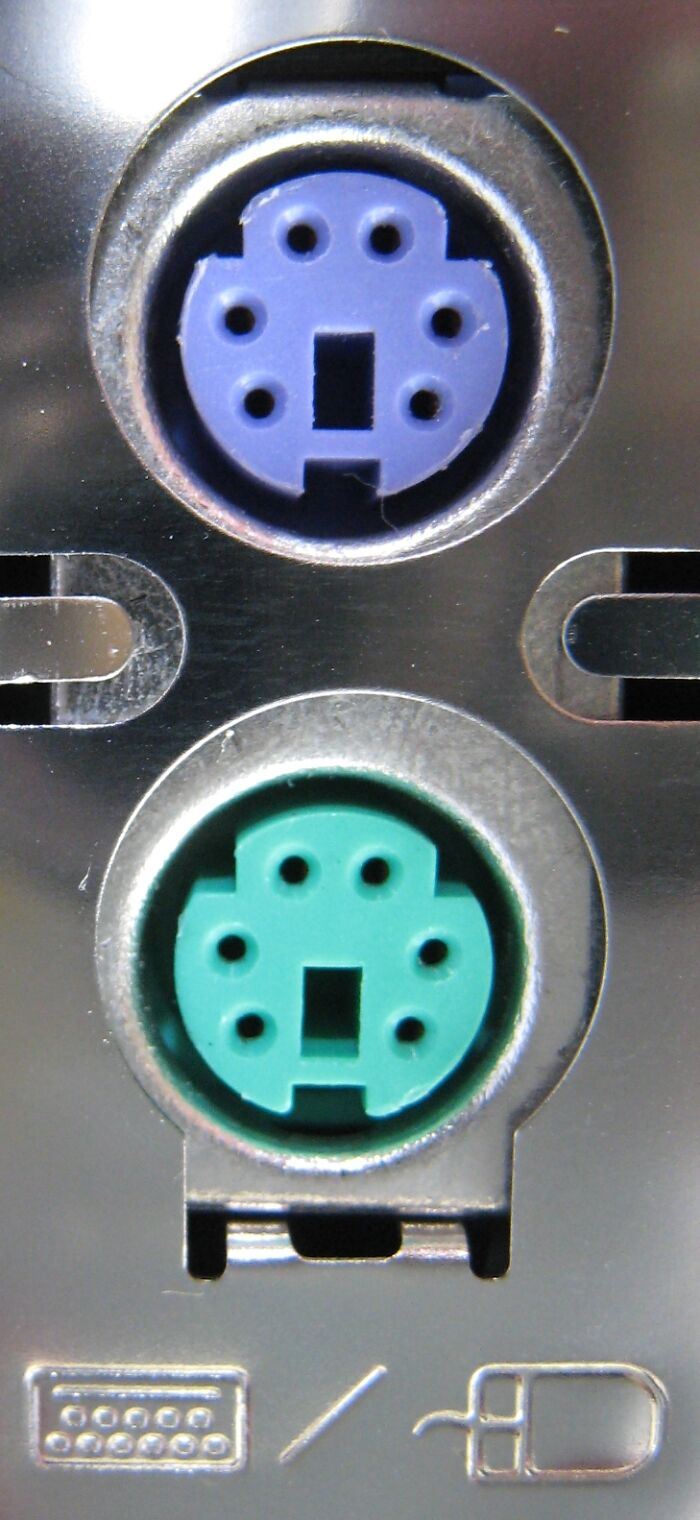 Close-up of old gadgets PS/2 keyboard and mouse ports on a computer back panel, showing vintage technology connectors.