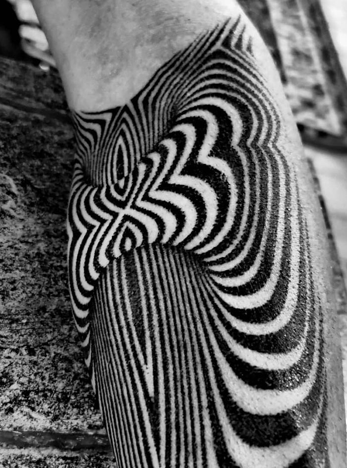 Optical illusion tattoo with black and white stripes creating a mind-bending design on the skin.