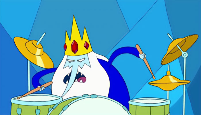 Ice King from Adventure Time playing drums with a focused expression in an animated blue icy background.