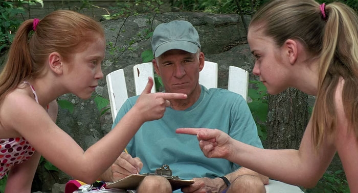 Tom Baker sitting and looking at girls that points at each other from Cheaper by the Dozen