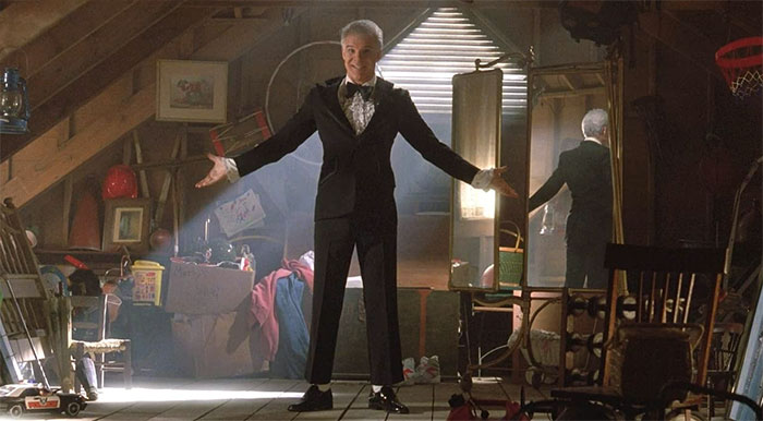 Scene from Father Of The Bride movie showing a man in a tuxedo in an attic, celebrating wedding movies and love.