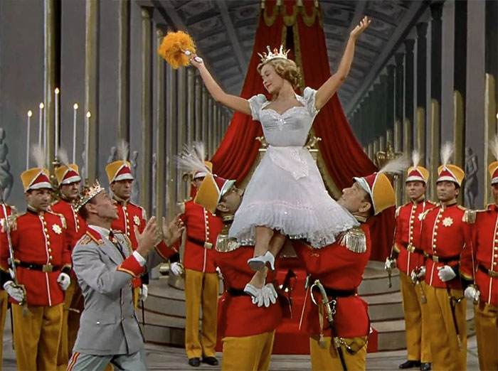 Scene from Royal Wedding movie featuring a joyful bride lifted by soldiers, showcasing classic wedding movies celebration.
