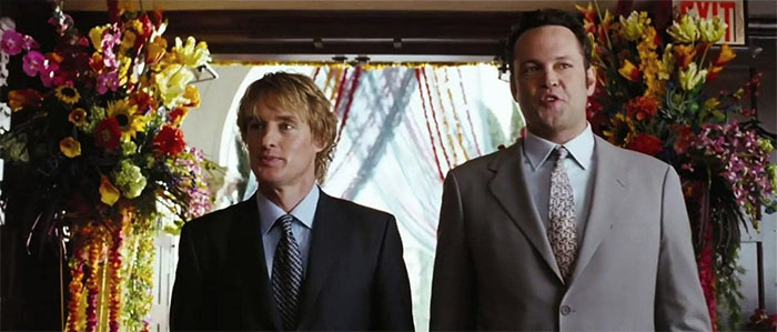 Scene from Wedding Crashers movie featuring two men in suits at a wedding, celebrating love in wedding movies.