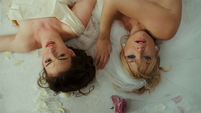 Scene from Bride Wars wedding movie featuring two brides lying on the floor with scattered rose petals, celebrating love.