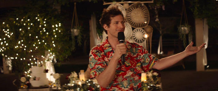 Scene from Palm Springs movie showing a man in a colorful shirt speaking at a wedding celebration of love.